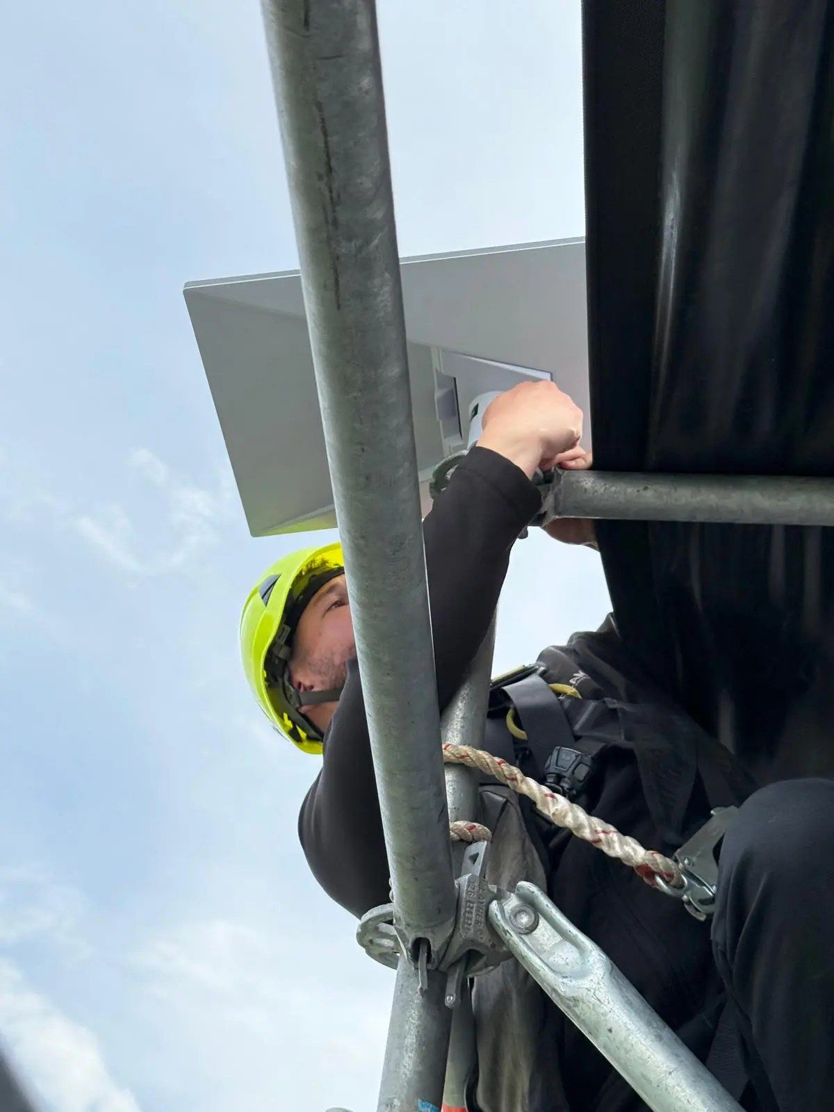 Técnico de DroneSevilla instalando una antena en andamio en altura